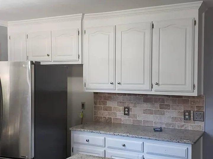 The same kitchen with the cabinets refinished white, unchanged granite and backsplash
