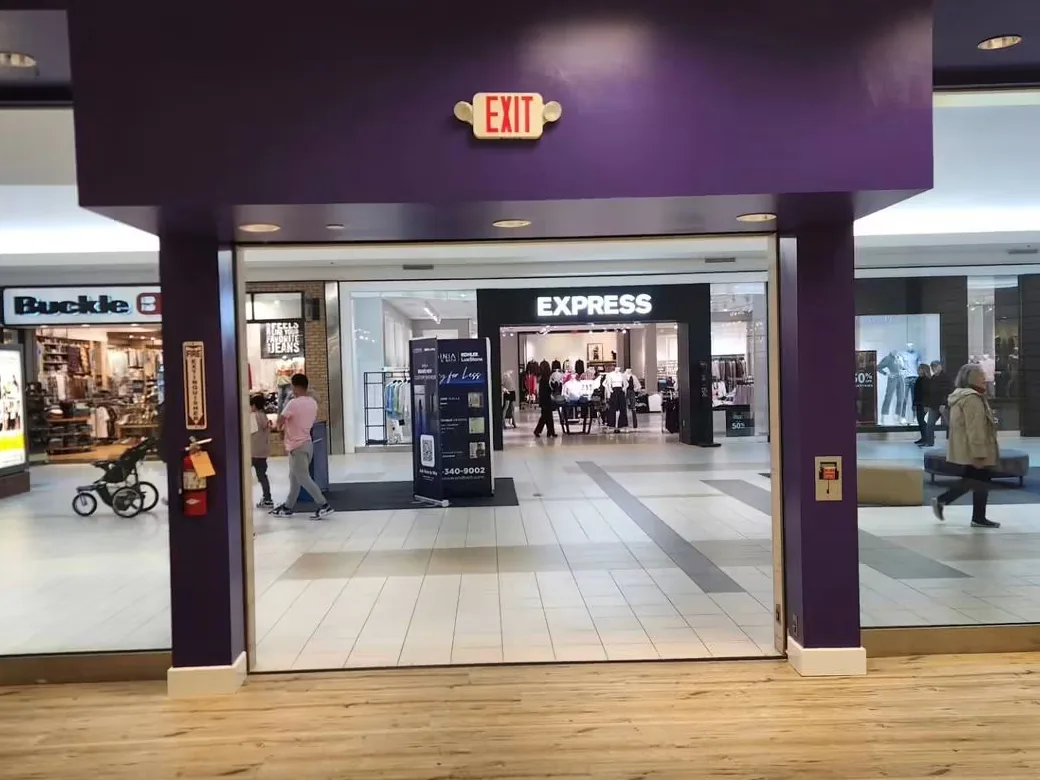 A mall retail unit before work, bulkhead and columns in the outgoing tenant’s dark purple