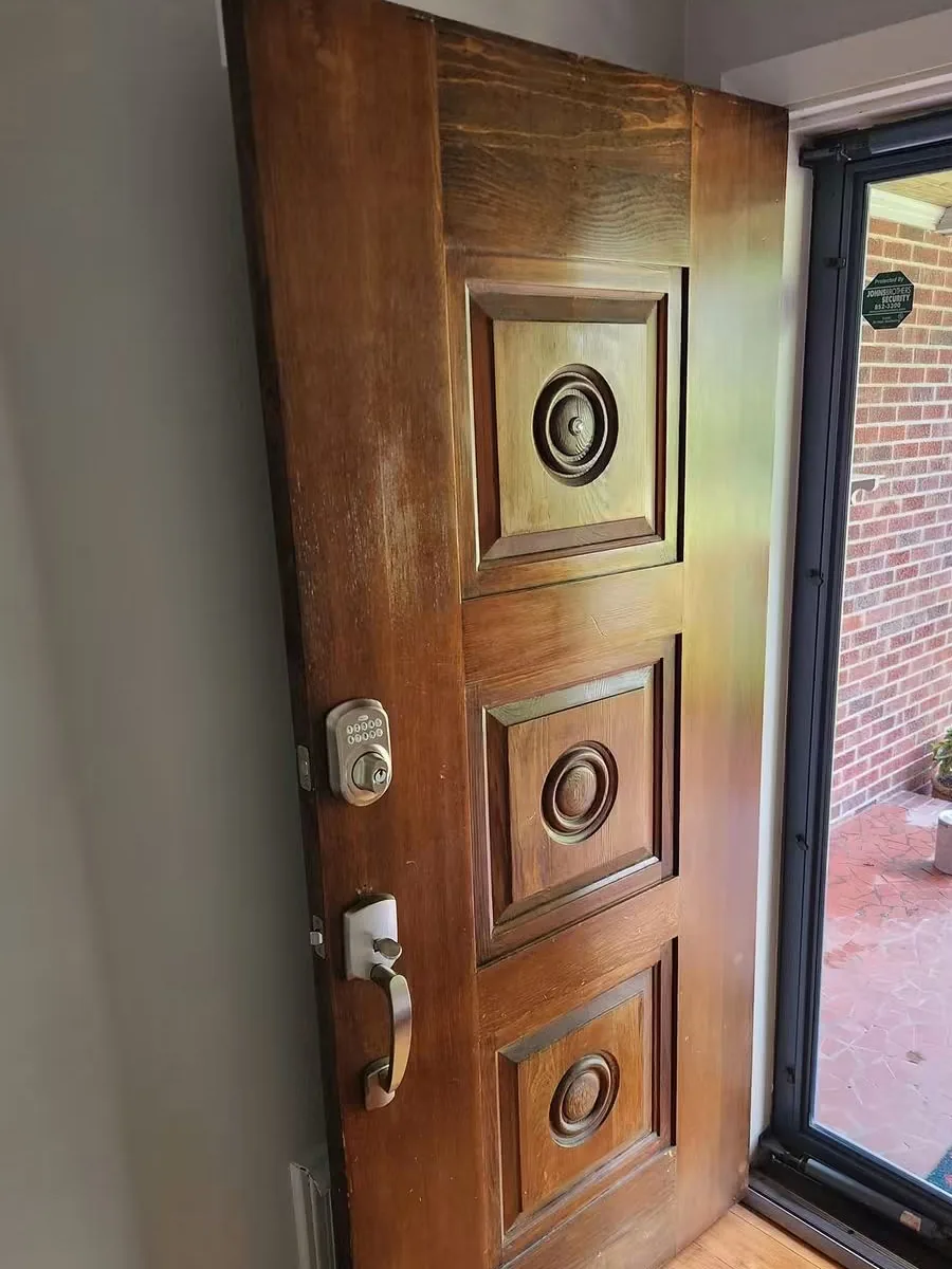 Raised-panel front door with the old stain sun-bleached and patchy across the stiles