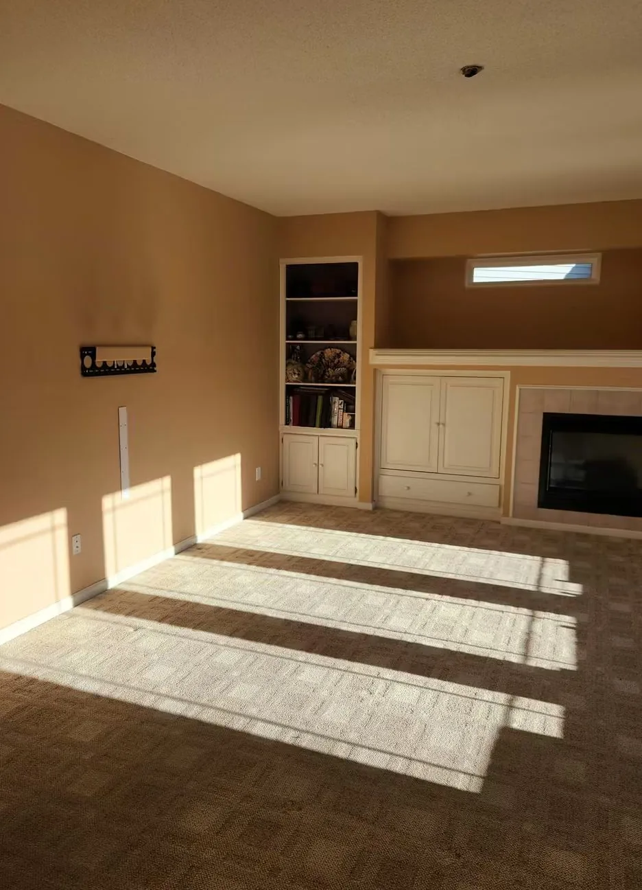 Living room in the original tan, built-in shelving and fire surround, carpet bare
