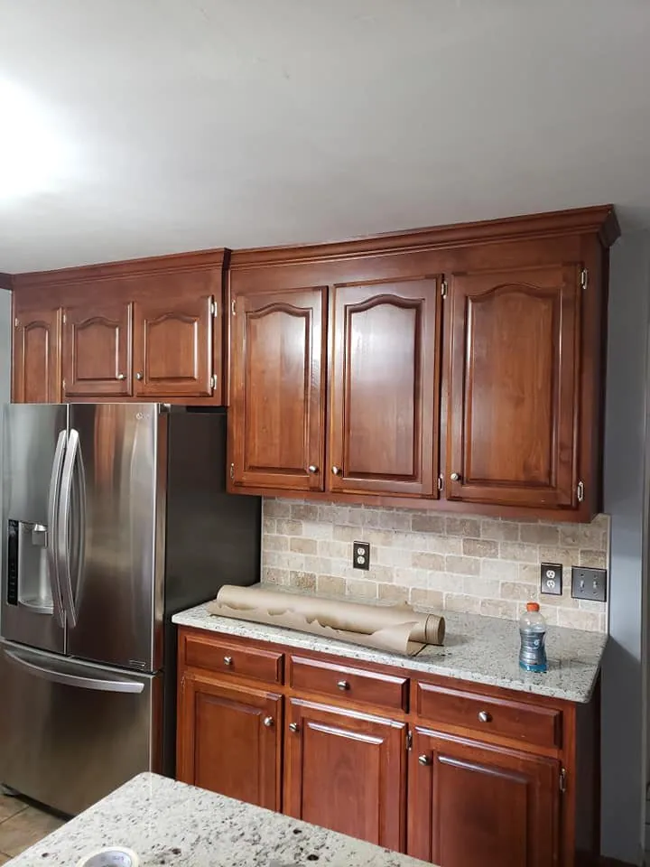 Kitchen with cherry-stained raised-panel cabinets, stone tile backsplash and granite countertops