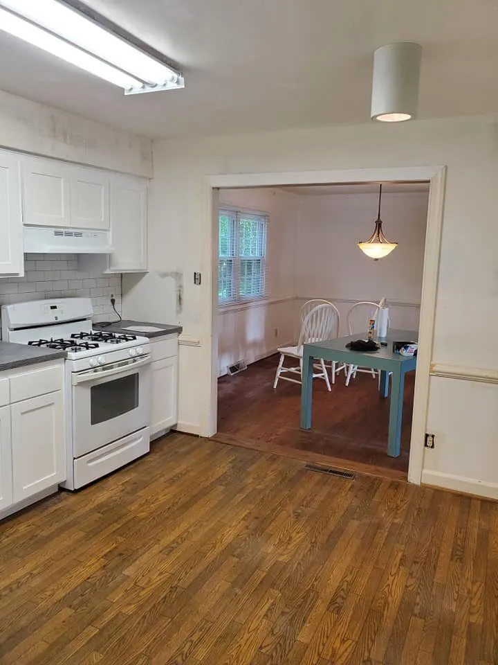 Kitchen with white shaker cabinets, subway tile backsplash and gas range beside an open dining room