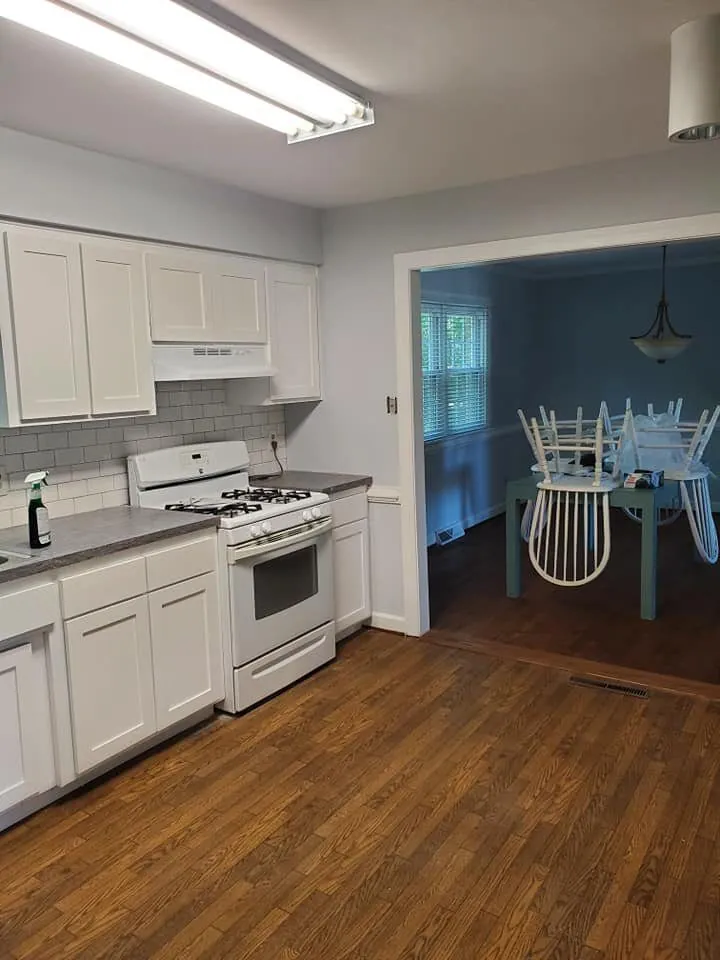 Kitchen with white shaker cabinets, gray counters and subway tile backsplash beside a teal dining room