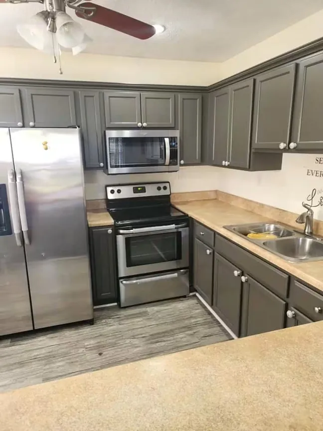 The refinished gray kitchen from the far corner, the peninsula and the wall cabinets carried through in the same color