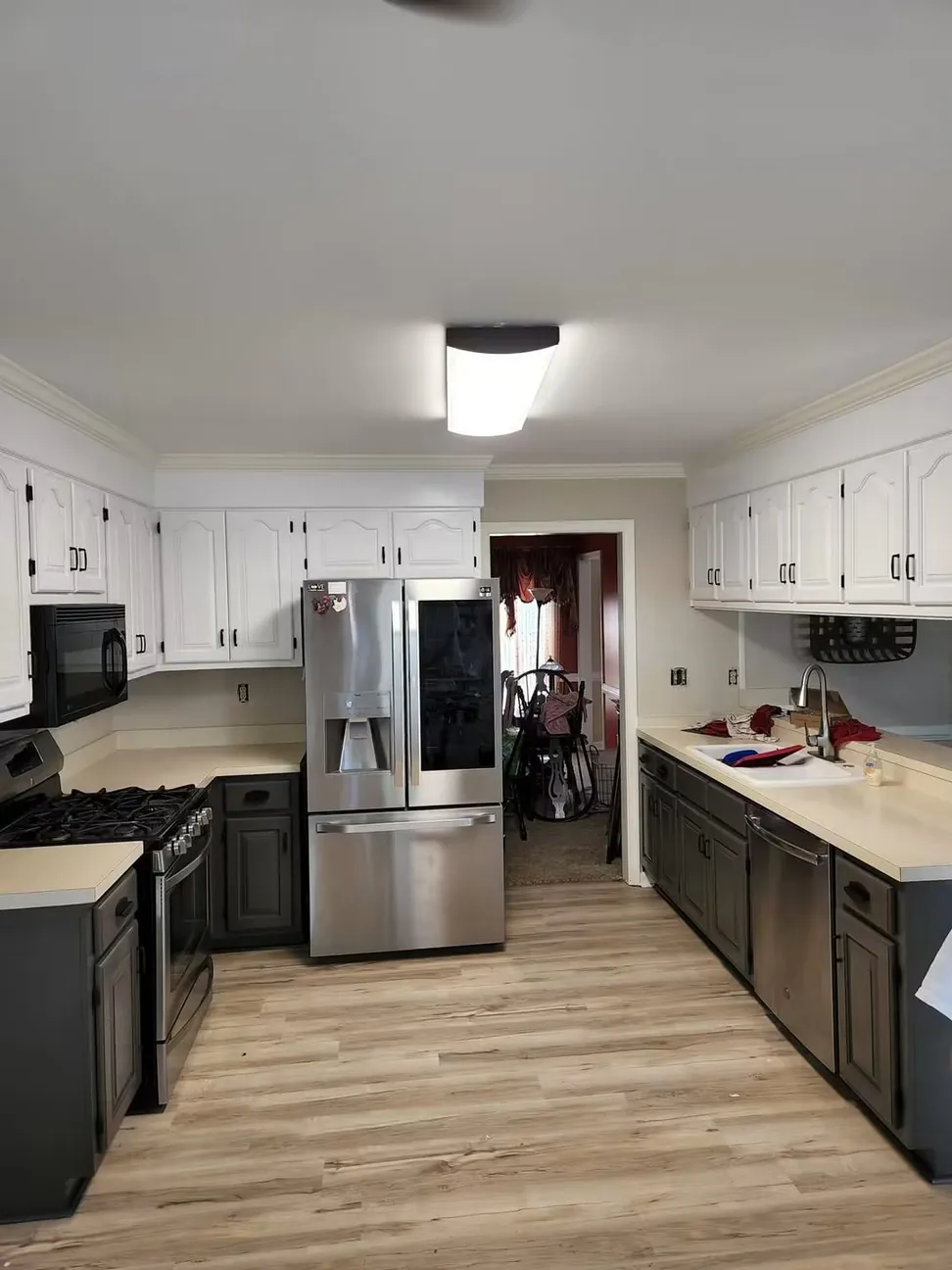 The finished galley kitchen end to end, white wall cabinets over charcoal bases and new flooring
