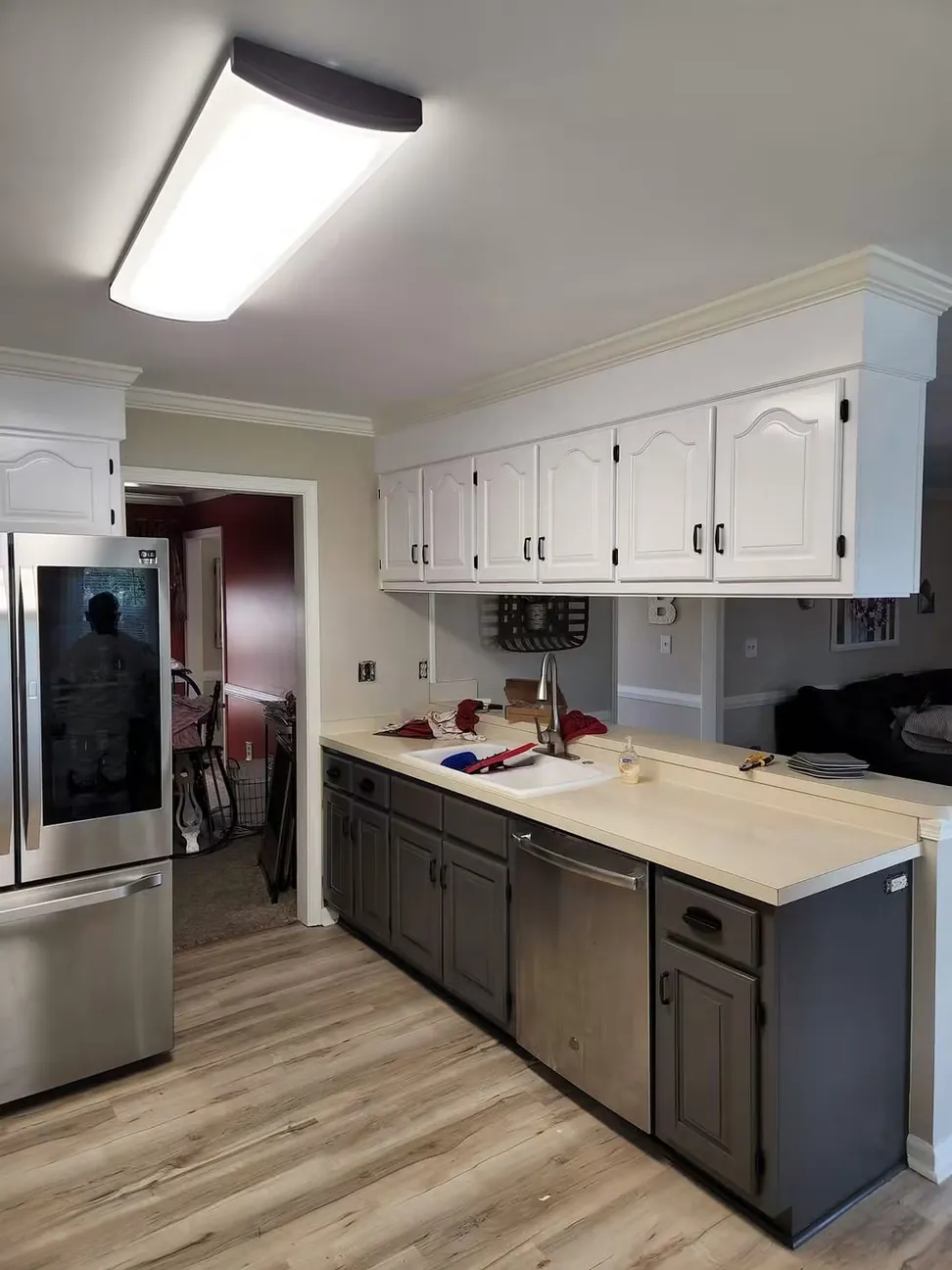 The long cabinet run finished, white above and charcoal below with the countertop and sink untouched
