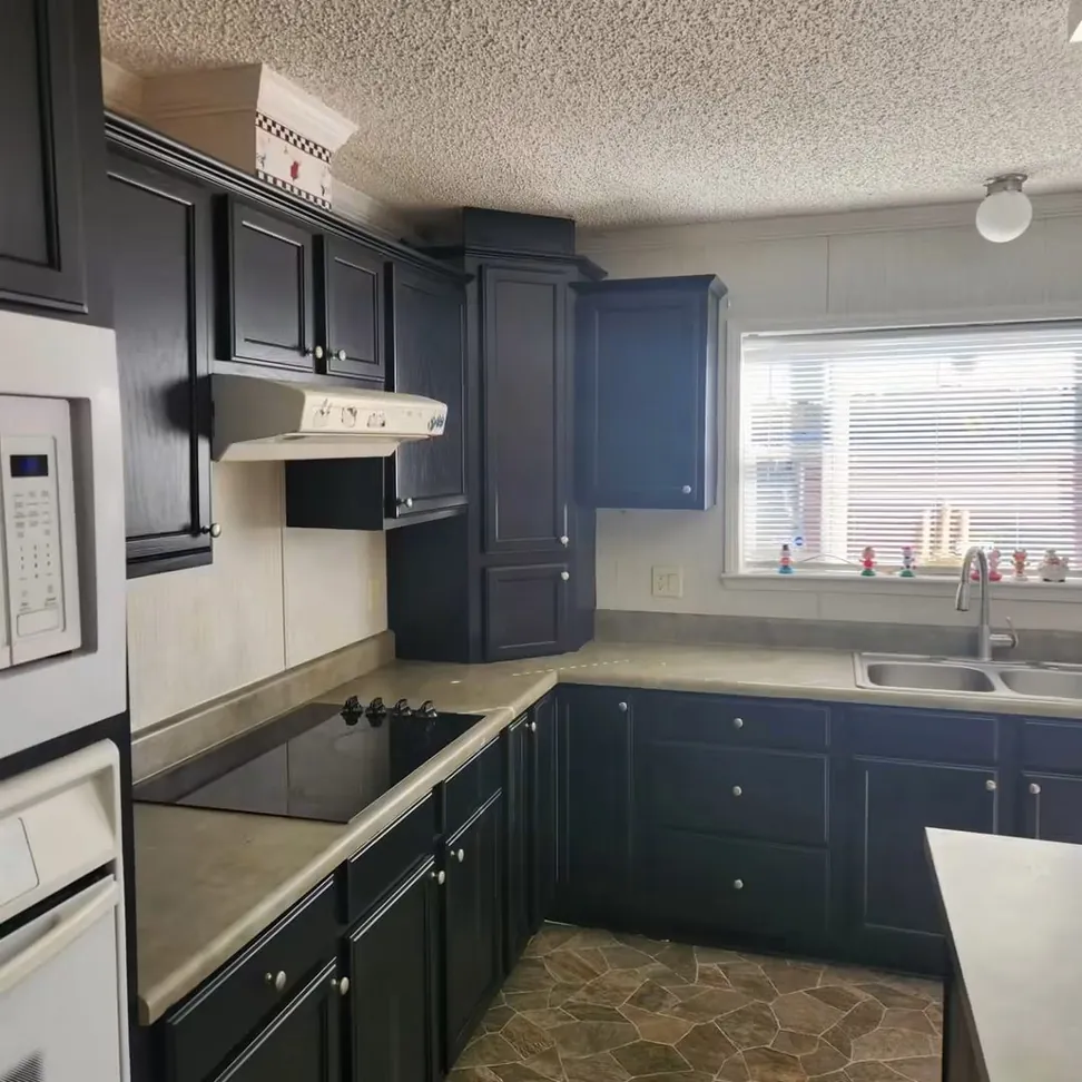 Oak kitchen cabinets refinished in navy, the countertop, cooktop and stone-effect floor all as they were