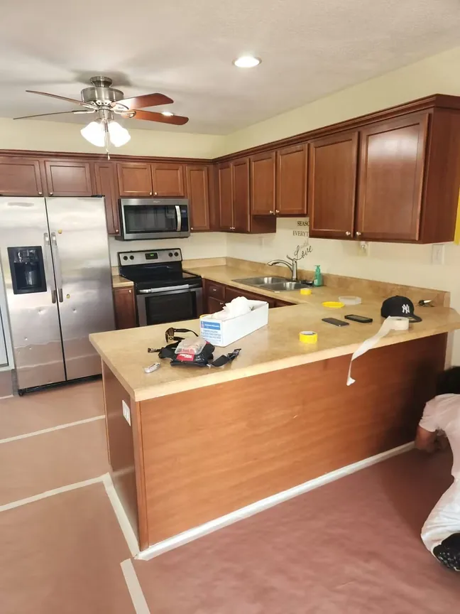 The same kitchen from the far corner before work, cherry cabinets and a stained peninsula end panel with the floor papered