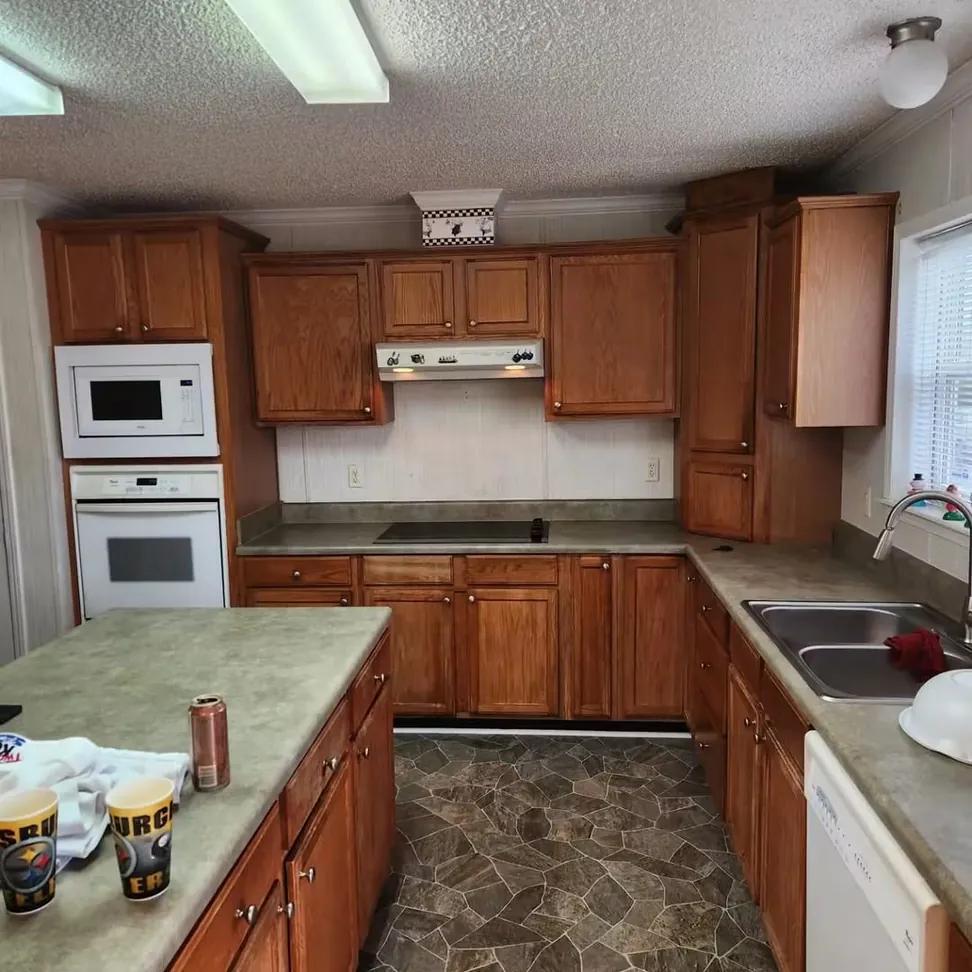 The same kitchen before work, honey oak wall and base cabinets around the island with the wall ovens already in place