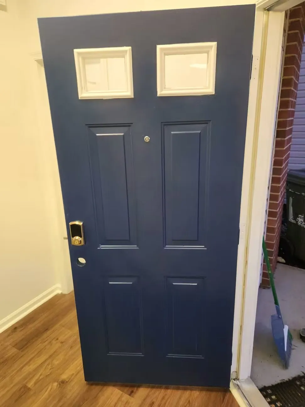 Front entry door finished in deep navy with the cream glazing bars and brick surround left as they were