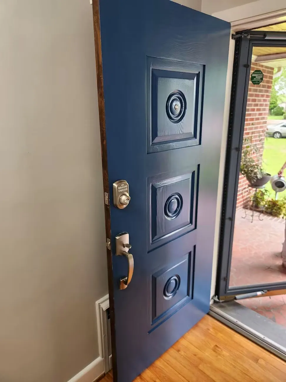 Raised-panel front door finished navy, the original brass medallions and handleset refitted