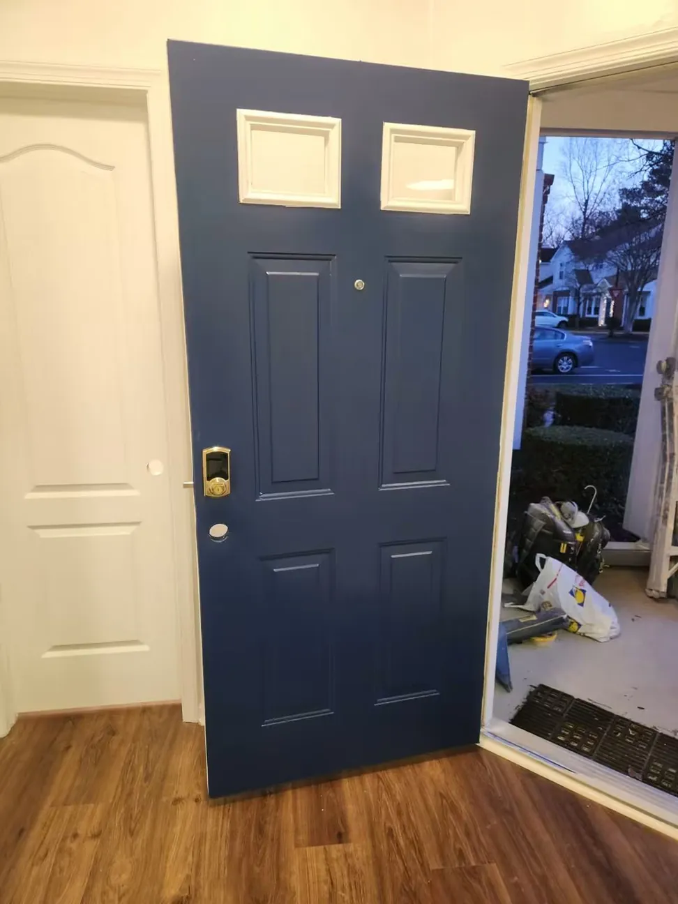 The same door finished in navy from inside the hall, the brass handleset back on and the light frames cut in white