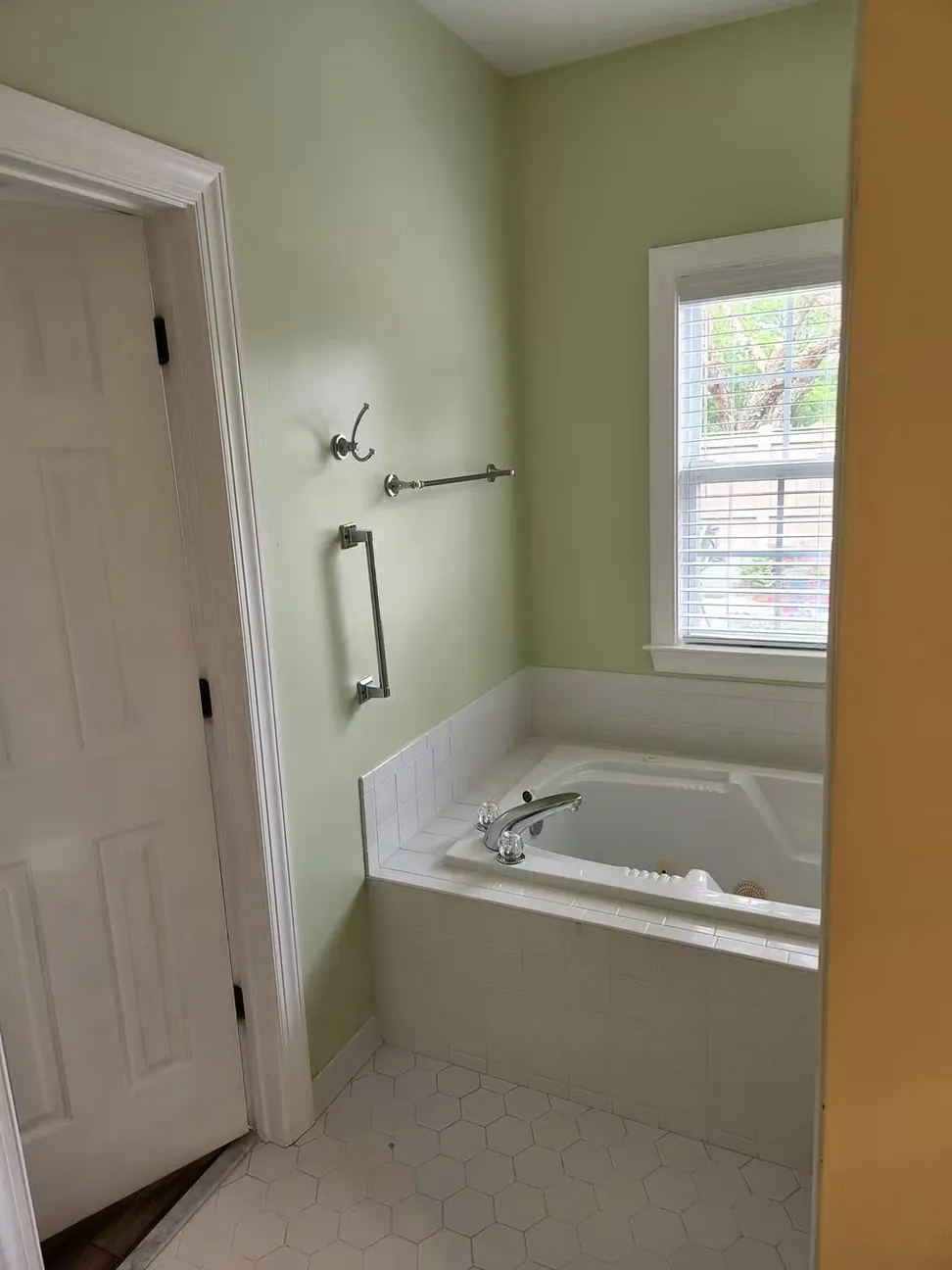 Bathroom in a soft sage with the tub surround, door and trim in white