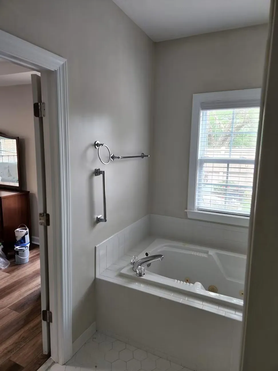 Bathroom and adjoining bedroom in the same gray, cut in around the tub surround and door casing