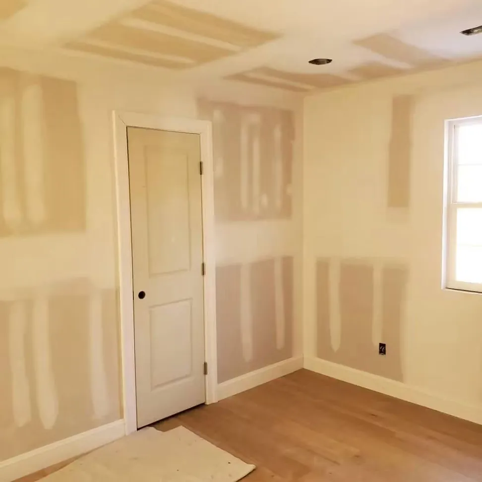 The same room primed, every joint and screw line still showing through the first coat