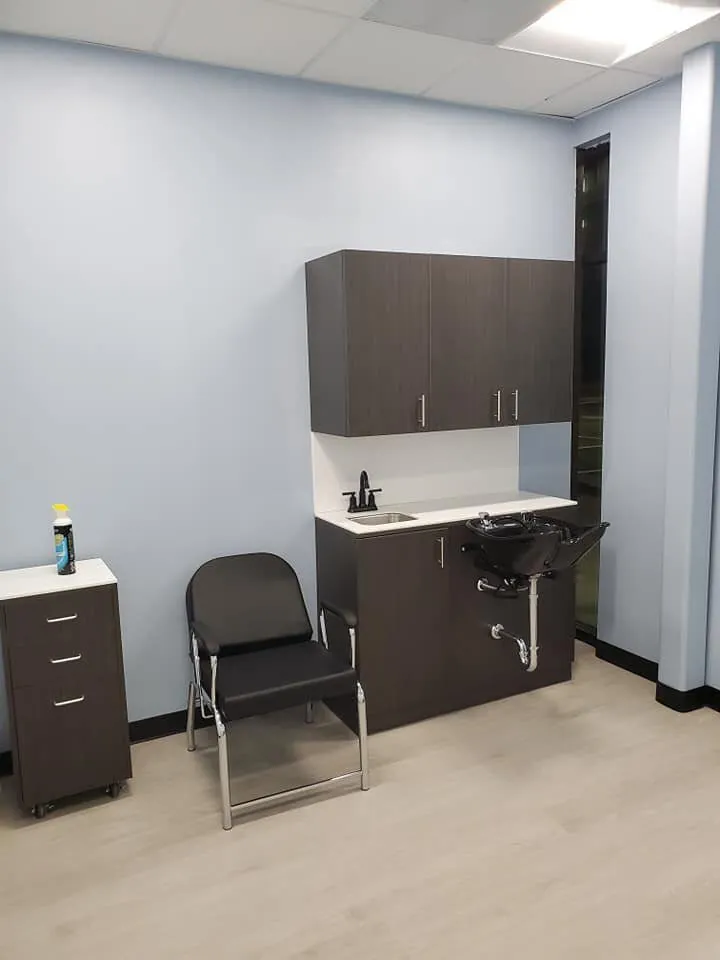 Salon room with light blue walls, dark wood cabinets, shampoo bowl sink and reclining chair