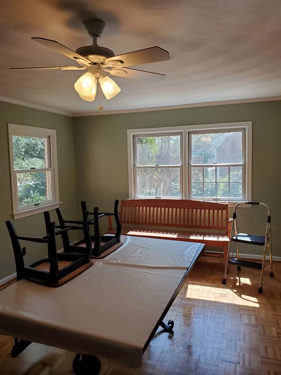 Dining room after the tongue-and-groove wall paneling was primed and painted sage green, the parquet floor protected throughout