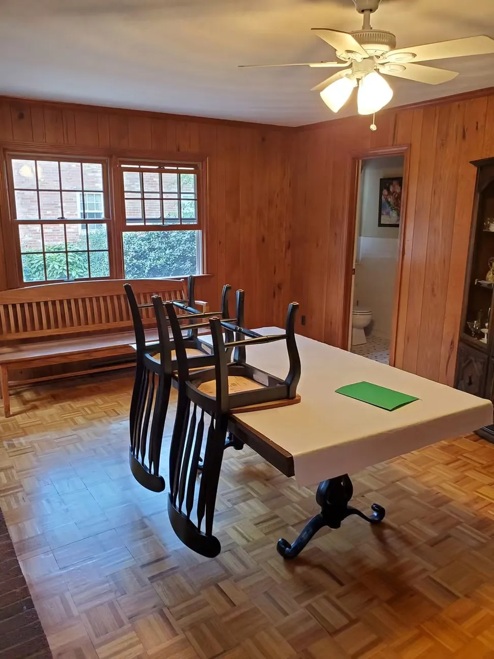 The same dining room before work, dark varnished wood paneling from floor to ceiling