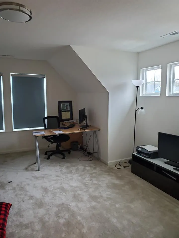 Bonus room with pale gray walls and sloped ceiling, desk with monitor and black media console