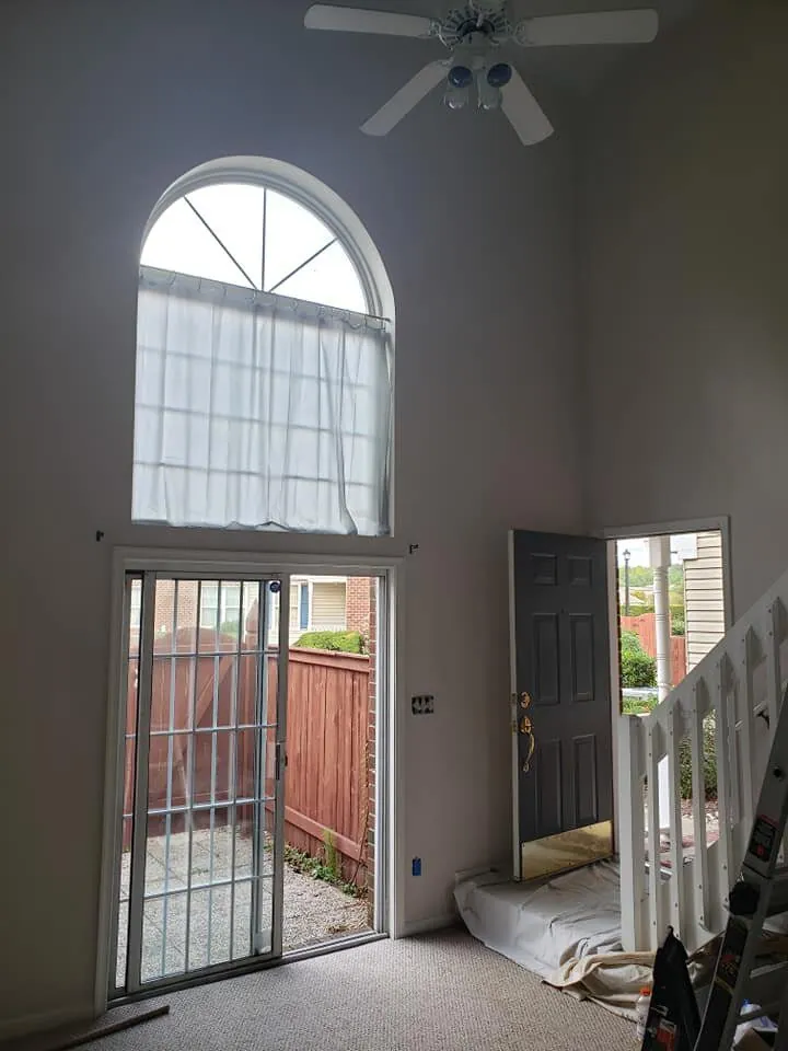 Two-story living room with gray walls, arched window, sliding glass door and gray painted front door