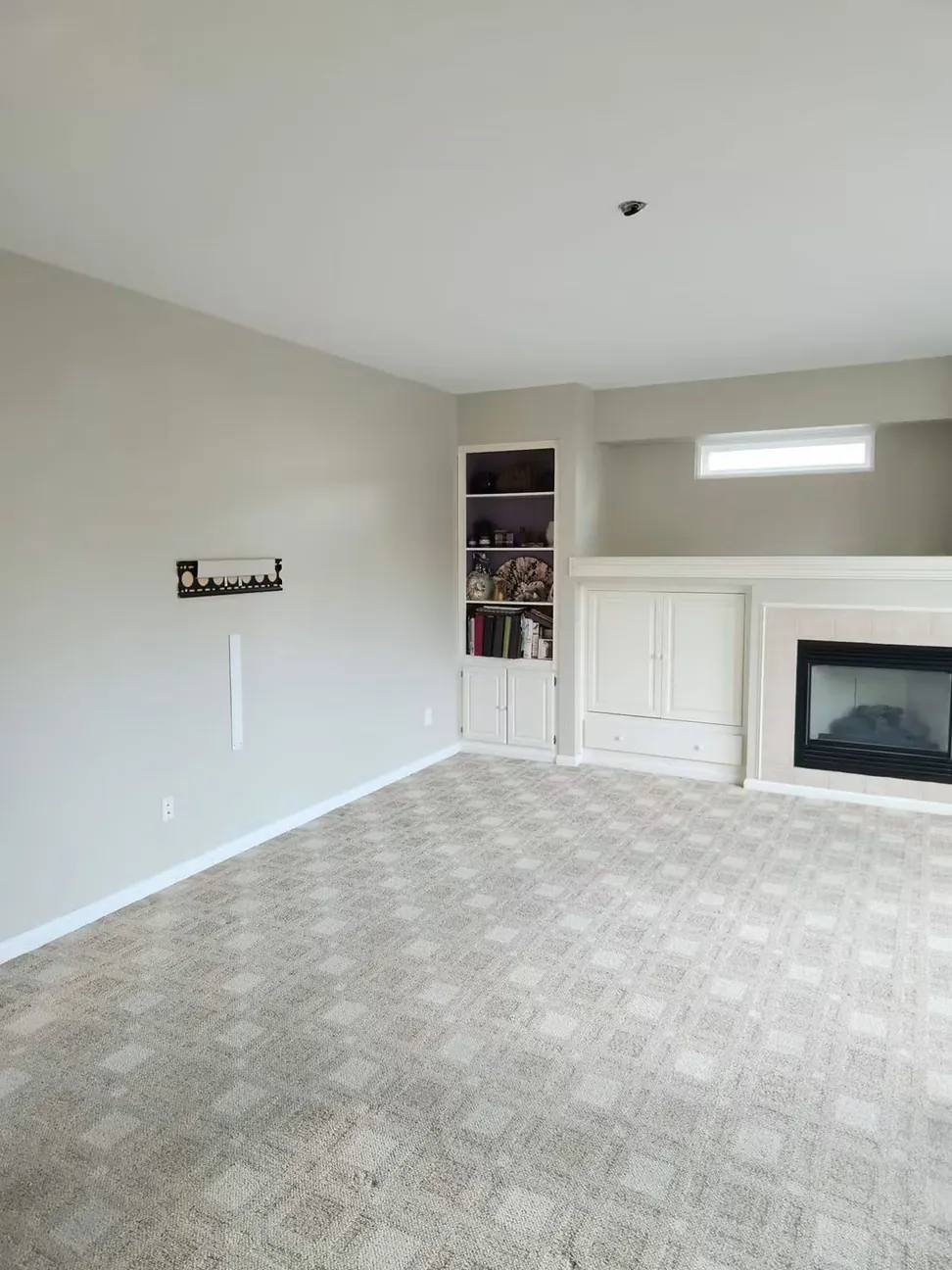 Living room repainted from tan to a soft gray, the built-in shelving and fire surround cut in by hand