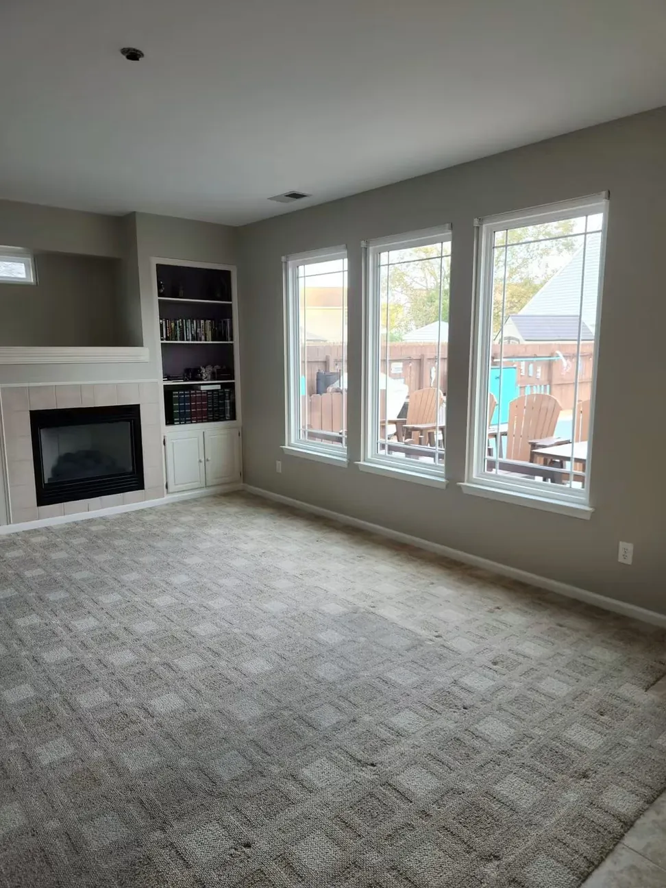 The repainted living room from the fireplace end, gray walls against white trim and a run of three windows