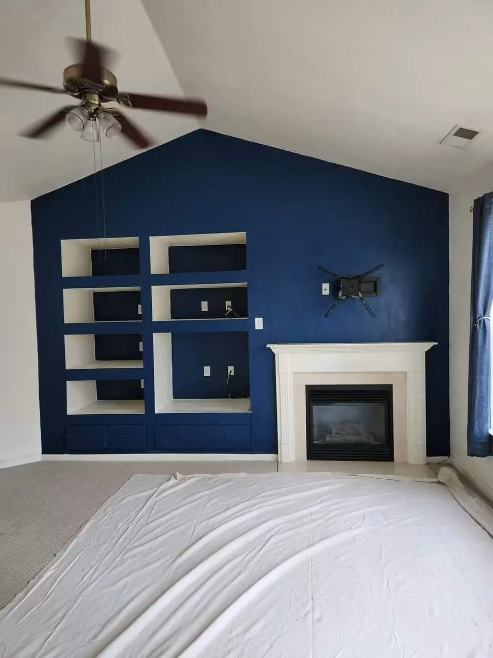 Great room with the gable wall and its built-in shelving finished in navy and the fire surround brought back to white