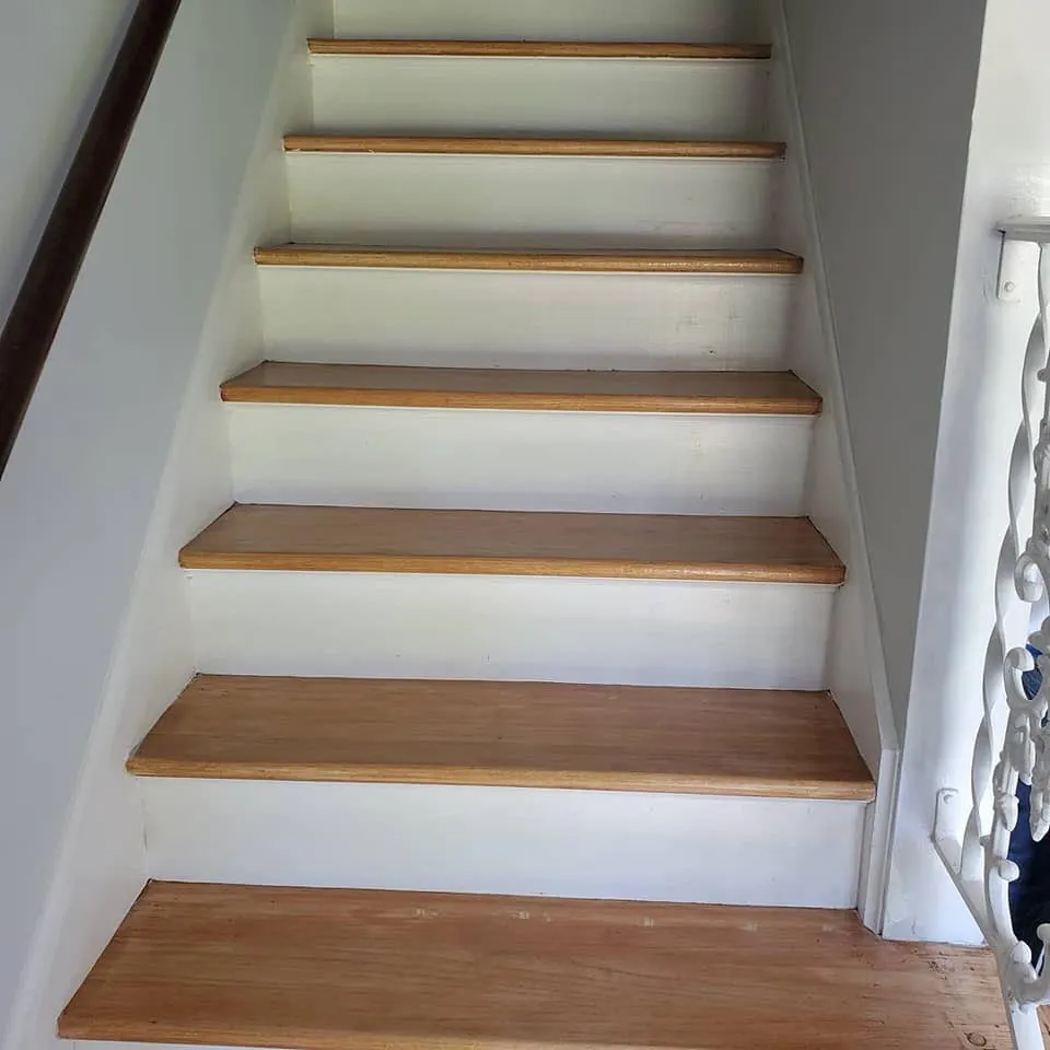 Staircase with freshly painted white risers and stringers beside natural stained wood treads