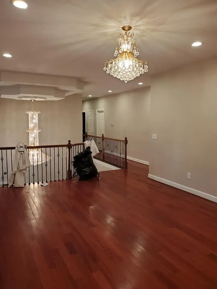 Upstairs landing with beige walls, cherry hardwood floor, and two crystal chandeliers