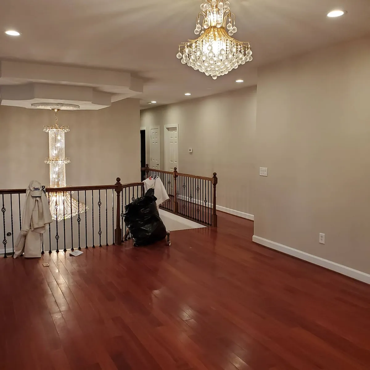 Upstairs landing painted greige with white trim, iron stair railing and two crystal chandeliers