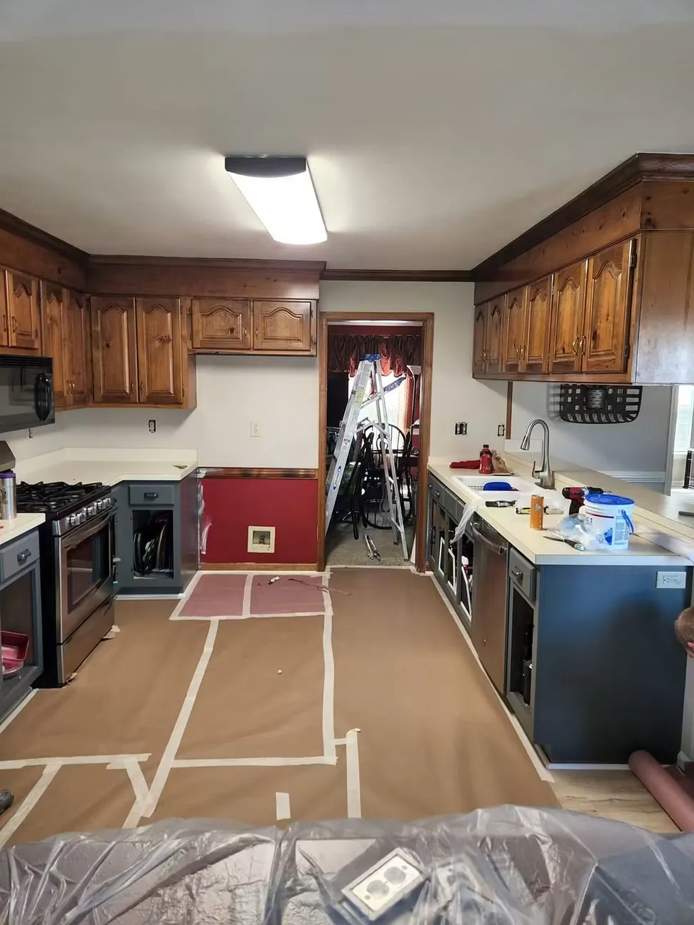 A kitchen floor papered and taped end to end before cabinet work starts, appliances and countertops covered