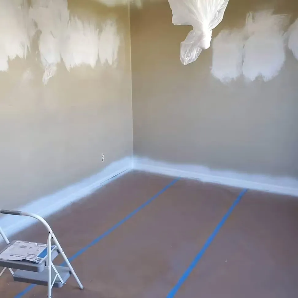A bedroom masked up before painting, floor papered wall to wall, edges taped and the light fixture bagged