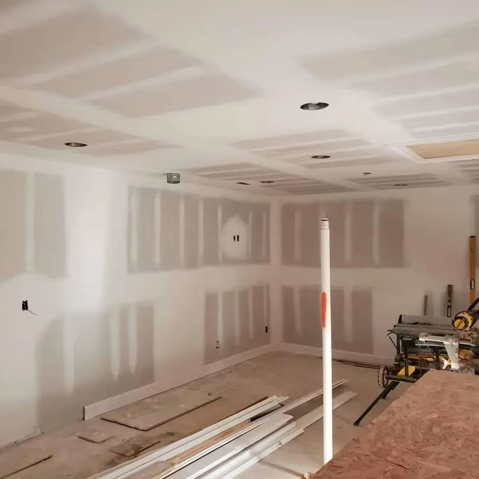 A new build at drywall stage, joints taped and sanded across the walls and coffered ceiling before priming