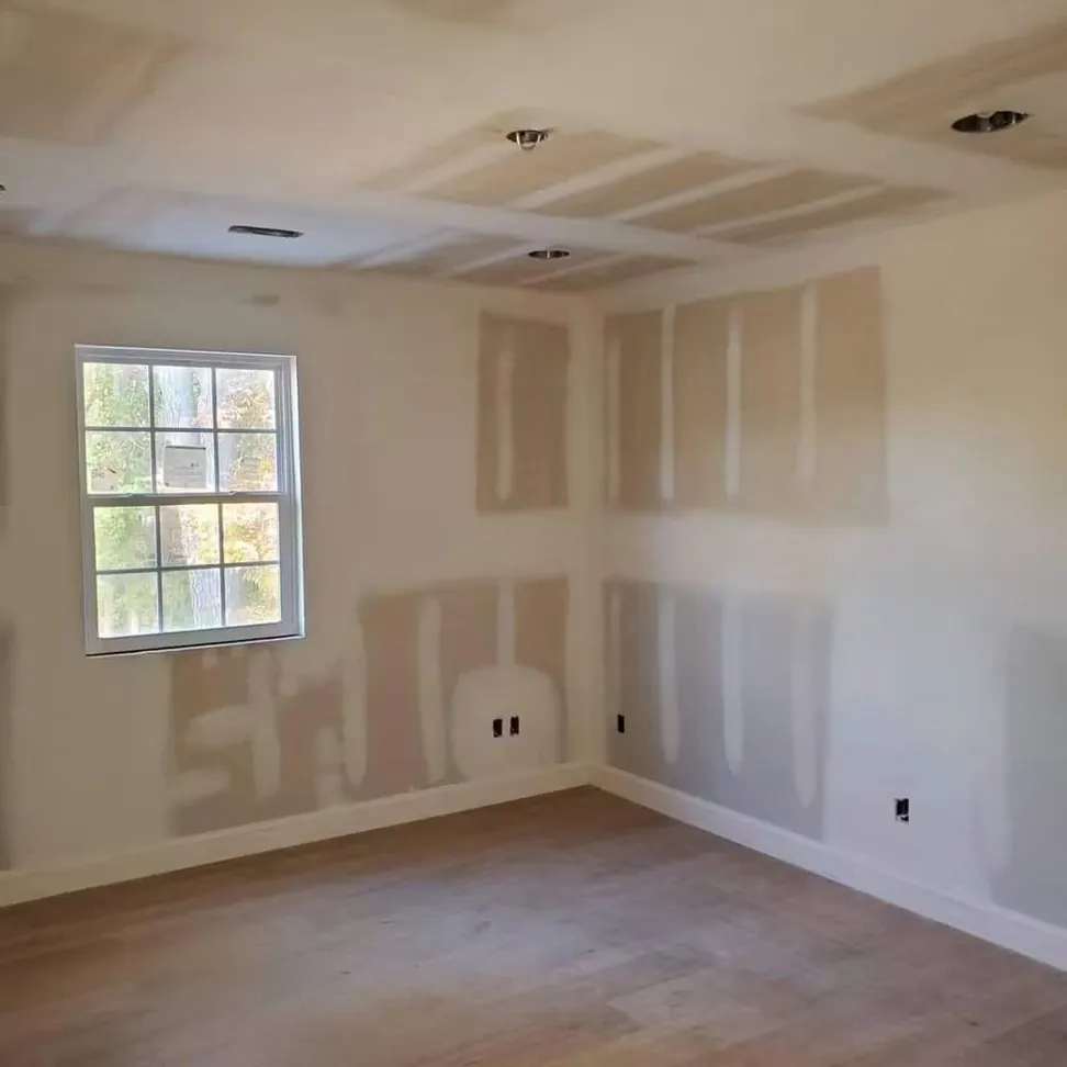A new build bedroom at drywall stage, patches feathered out around the sockets before the first coat